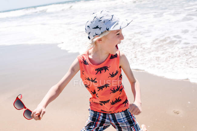 Хлопчик на пляжі, коли морські хвилі йдуть до нього — стокове фото