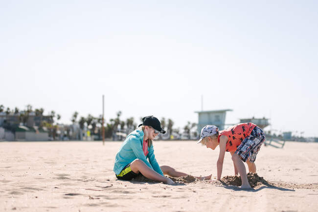 Sorella e fratello che giocano nella sabbia sulla spiaggia — Foto stock