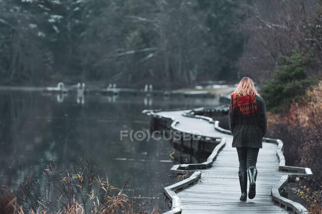 Rear view of woman walking on walkway, Lillooet Lake, British Co — Stock Photo