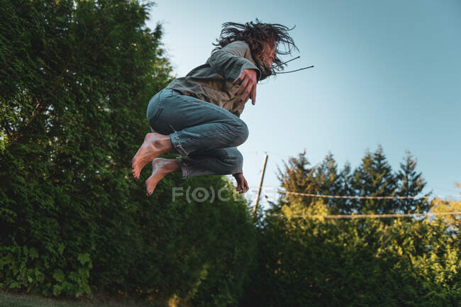 Mujer joven en el aire, saltando en el trampolín - foto de stock