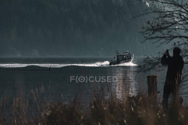 Canada, British Columbia, Squamish, Man photographing fishing boat in inlet — Stock Photo