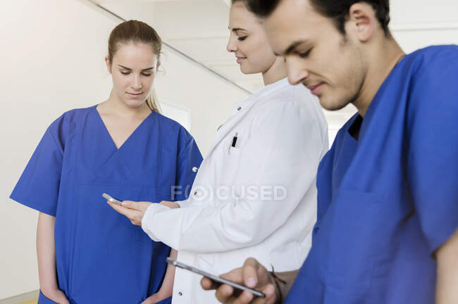 Германия, Бавария, Мюнхен, Молодой медицинский персонал с использованием смартфонов в больнице — стоковое фото