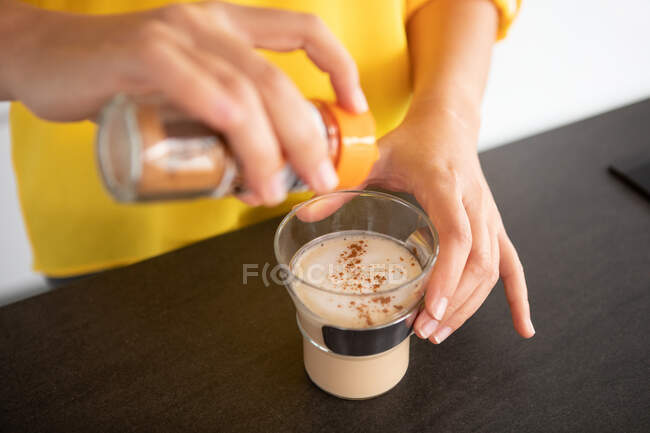 Portugal, Lisbon, Close-up of woman's hands sprinkling coffee with cinnamon — Stock Photo