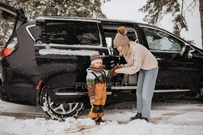 Канада, Онтарио, мать одевает дочь (2-3 года) в зимнюю одежду рядом с машиной — стоковое фото