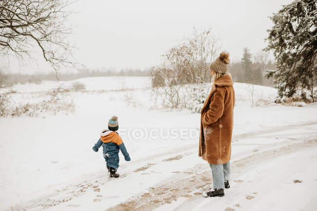Canada, Ontario, Mother and son (12-17 months) on snowy road — Stock Photo