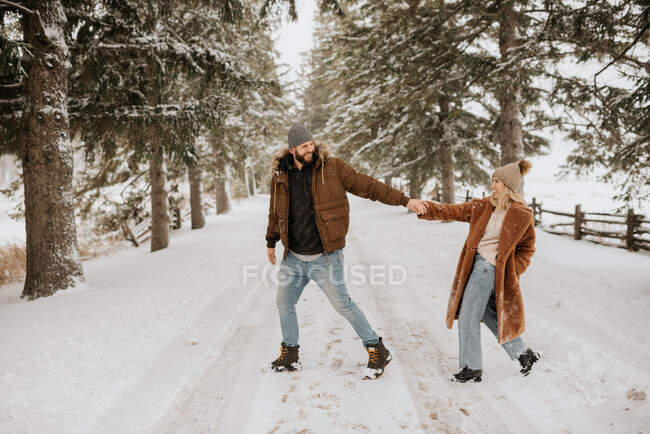 Канада, Онтаріо, подружжя, яке посміхається, тримаючись за руки на зимовій прогулянці. — стокове фото