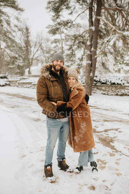 Канада, Онтарио, обнимающая пара, стоящая на снежной дороге — стоковое фото