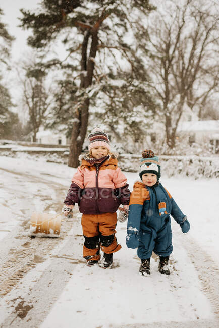 Brother (12-17 months) and sister (2-3) on snowy road — Stock Photo