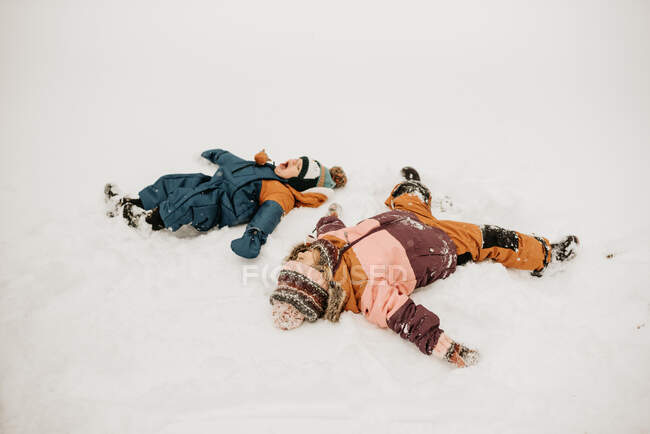 Canadá, Ontario, Hermano (12-17 meses) y hermana (2-3) haciendo ángeles de nieve - foto de stock
