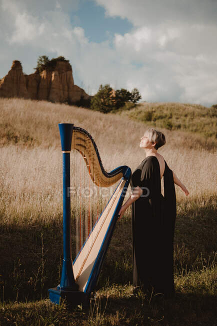 Itália, Toscana, Firenze, Mulher em pé no campo com harpa — Fotografia de Stock