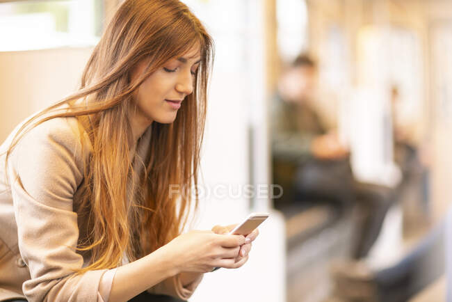 Alemania, Berlín, Mujer joven usando el teléfono inteligente - foto de stock