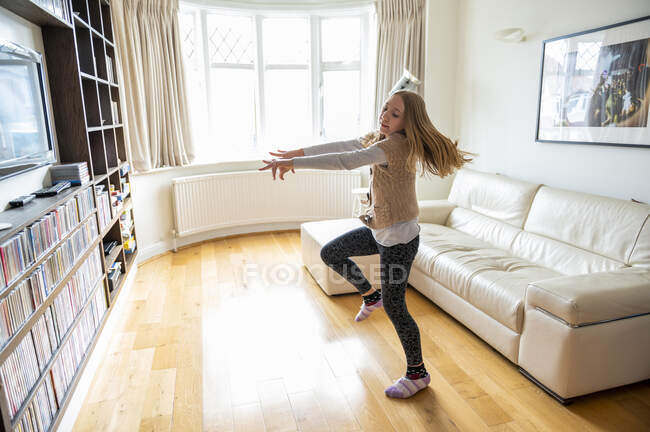Великобритания, Суррей, Девочка (10-11 лет) танцует перед телевизором в гостиной — стоковое фото