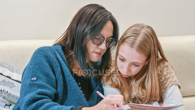 Mãe ajudando filha (10-11) com lição de casa — Fotografia de Stock