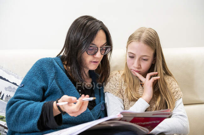 Reino Unido, Surrey, Madre ayudando a su hija (10-11) haciendo los deberes en casa - foto de stock