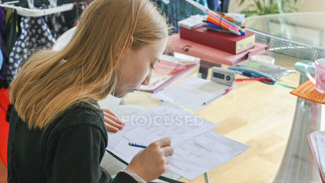 Великобритания, Суррей, девочка (10-11 лет), выполняющая домашнюю работу — стоковое фото