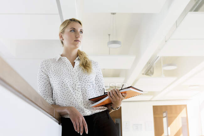 Germany, Bavaria, Munich, Young businesswoman standing in office — Stock Photo