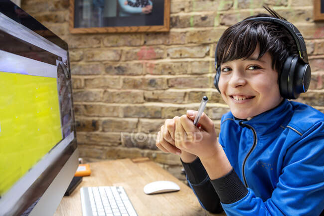Великобритания, мальчик Смилинг (10-11 лет) в наушниках с онлайн-уроком — стоковое фото