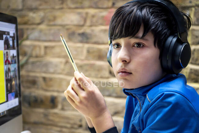 Royaume-Uni, Garçon (10-11) dans les écouteurs ayant une leçon en ligne — Photo de stock