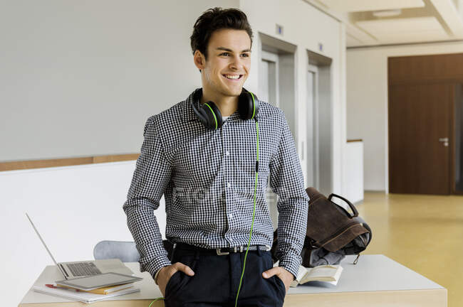 Germany, Bavaria, Munich, Smiling young man standing at desk — Stock Photo