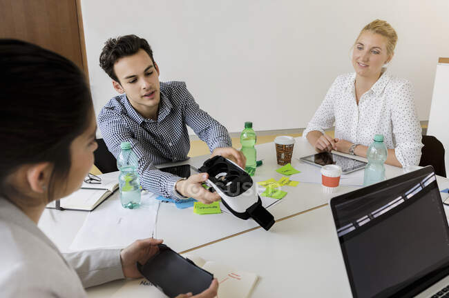 Germany, Bavaria, Munich, Presenting VR Goggles during office meeting — Stock Photo