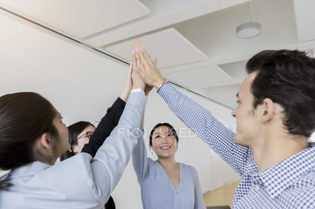 Alemania, Baviera, Munich, Gente de negocios haciendo high-five juntos en el cargo - foto de stock