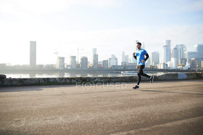 UK, London, Jogger running with downtown skyline in background — Stock Photo