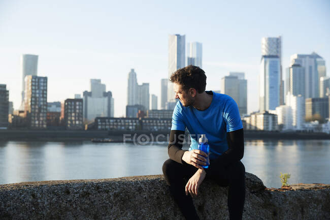 Reino Unido, Londres, Jogger mirando el horizonte del centro de la ciudad en segundo plano - foto de stock