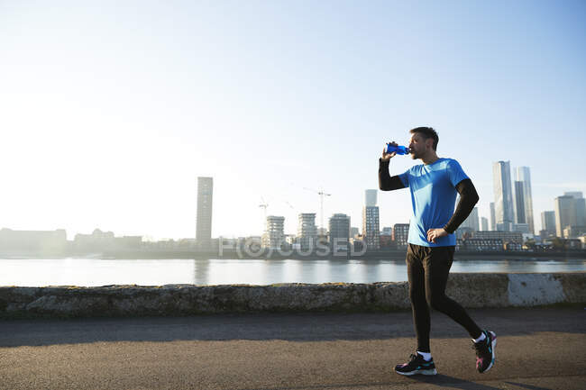 UK, London, Jogger drinking with downtown skyline in background — Stock Photo