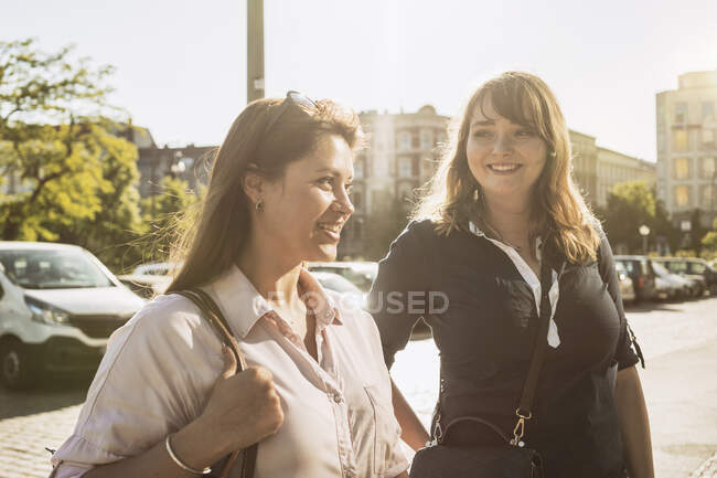 Alemania, Berlín, Dos mujeres en la calle de la ciudad - foto de stock