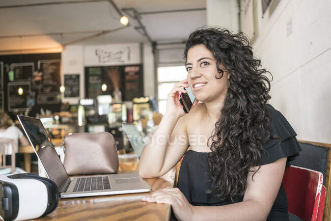 Mulher usando telefone e laptop no café — Fotografia de Stock