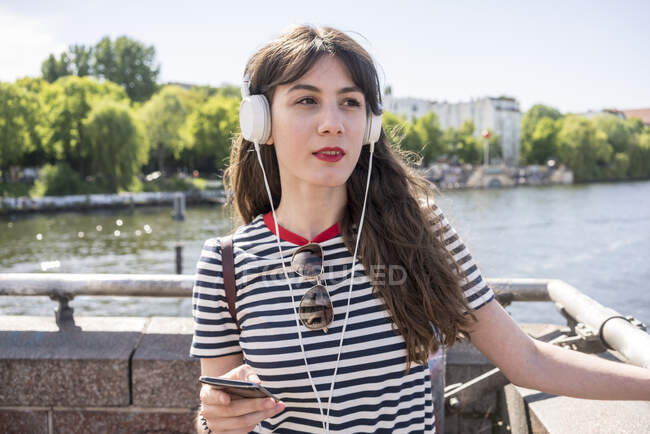Alemania, Berlín, Mujer joven con auriculares - foto de stock