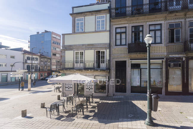 Portugal, Oporto, café vacío en la acera y plaza del casco antiguo en un día soleado - foto de stock