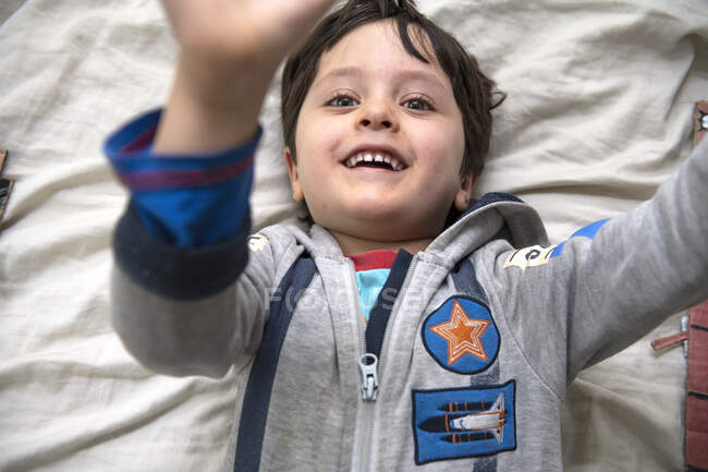 Reino Unido, Retrato de un chico sonriente acostado en la cama - foto de stock
