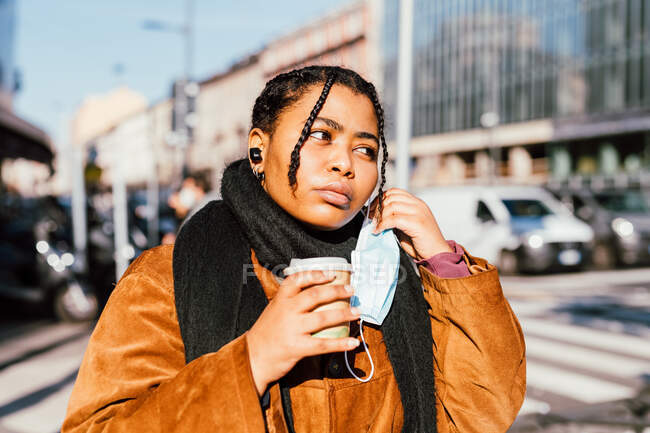 Italien, Junge Frau mit Mundschutz hält Einwegbecher im Freien — Stockfoto