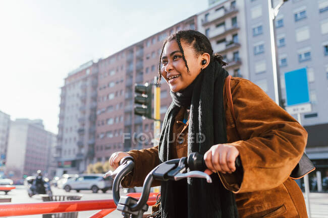 Italia, Mujer joven sonriente con bicicleta en la calle de la ciudad - foto de stock