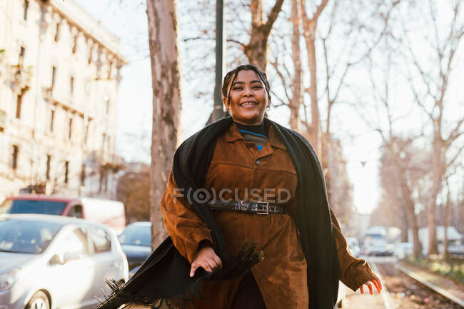 Italia, Mujer joven sonriente caminando en la acera - foto de stock