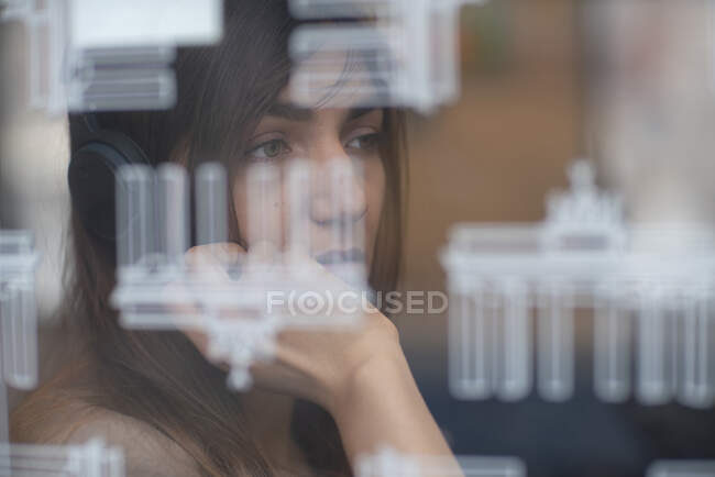 Alemania, Berlín, Mujer joven mirando por la ventana - foto de stock