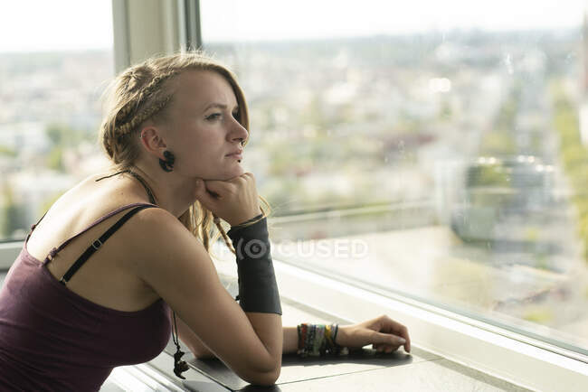 Giovane donna guardando fuori dalla finestra — Foto stock