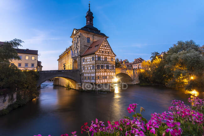 Deutschland, Bayern, Bamberg, Stadtgebäude mit Bogenbrücke in der Abenddämmerung beleuchtet — Stockfoto