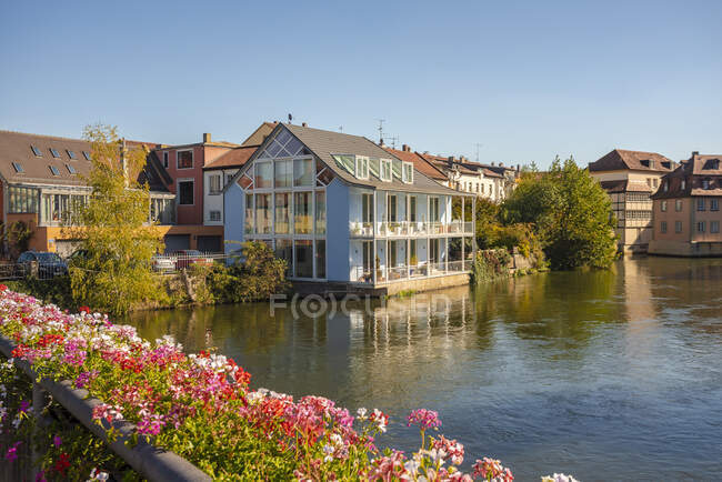 Germany, Bavaria, Bamberg, Flowers and townhouses by river — Stock Photo