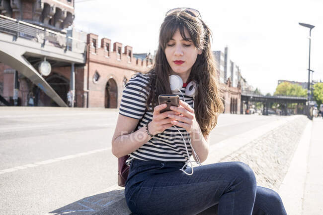 Германия, Берлин, молодая женщина с телефоном на улице — стоковое фото