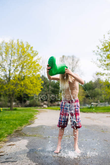 Kanada, Kingston, Junge ohne Hemd gießt Wasser aus Gummistiefel auf den Kopf — Stockfoto