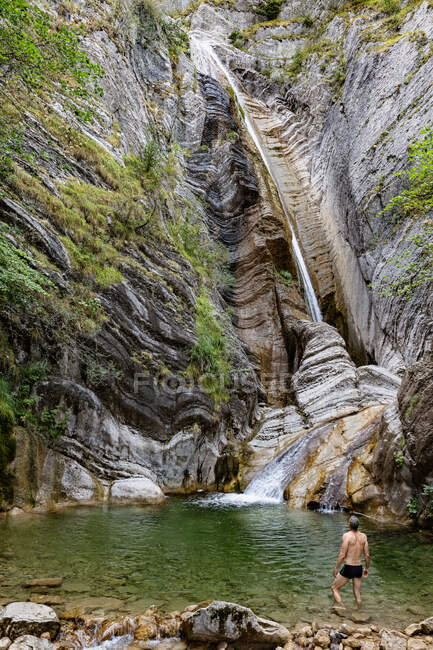 França, Alpes-de-Haute-Provence, Homem na lagoa olhando para a cachoeira na rocha erodida — Fotografia de Stock