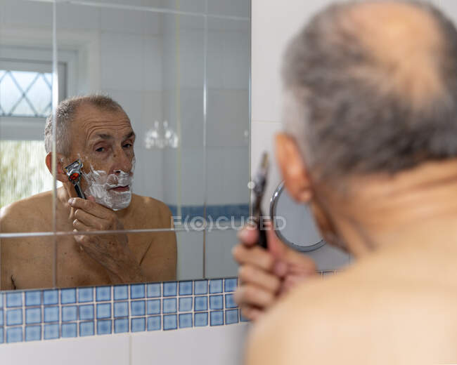 UK, East Sussex, Senior uomo rasatura davanti allo specchio del bagno — Foto stock
