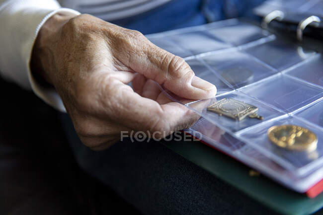 UK, East Sussex, Close-up of senior mans hand holding coin album — Stock Photo