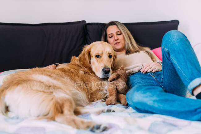 Italy, Young woman with dog relaxing on bed — Stock Photo