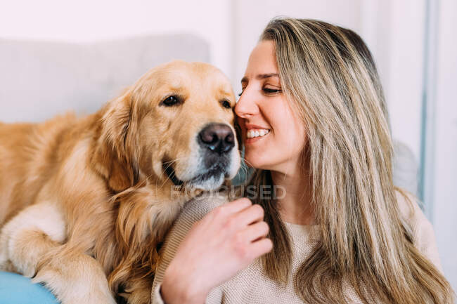 Italia, Mujer joven con perro en casa - foto de stock