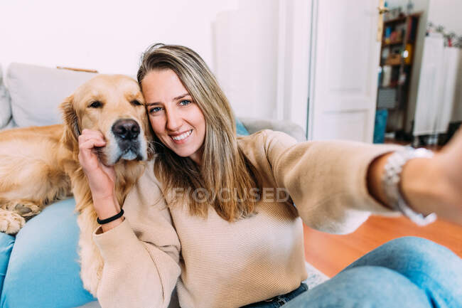 Italia, Retrato de mujer joven con perro en casa - foto de stock