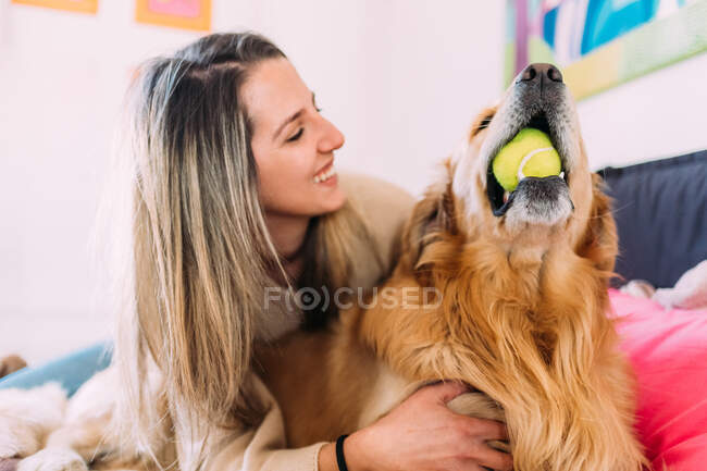 Италия, Молодая женщина играет с собакой дома — стоковое фото