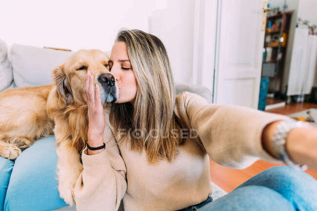 Италия, молодая женщина целует собаку дома — стоковое фото